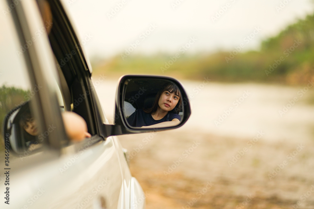 Young Asian girl is reflected in mirror of car at the riverside, Travel car in holiday