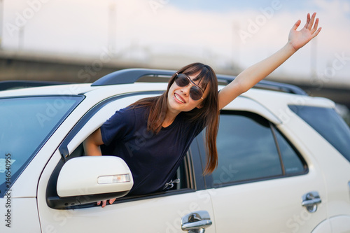 ํYoung Asian woman wearing sun glasses out of white SUV car window at the riverside, Travel car in vacation