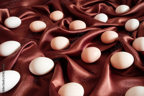 Brown chicken eggs lie on brown silk fabric photo