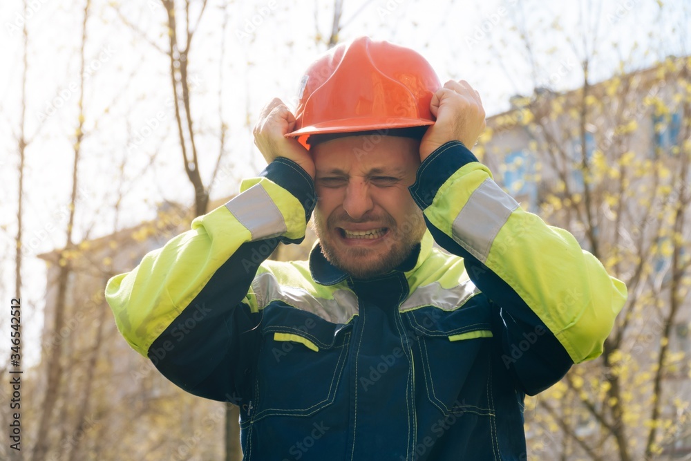 male builder in helmet closeup, upset in shock, holding his head. Fire fighting concept. house burned down male builder in helmet closeup, upset in shock, holding his head. Fire fighting concept. house burned down