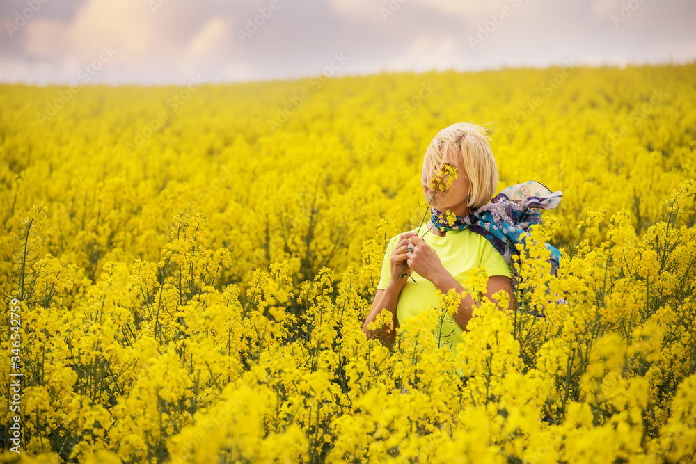 Middle-aged blonde woman among a bright yellow field of flowers. Middle-aged blonde woman among a bright yellow field of flowers.