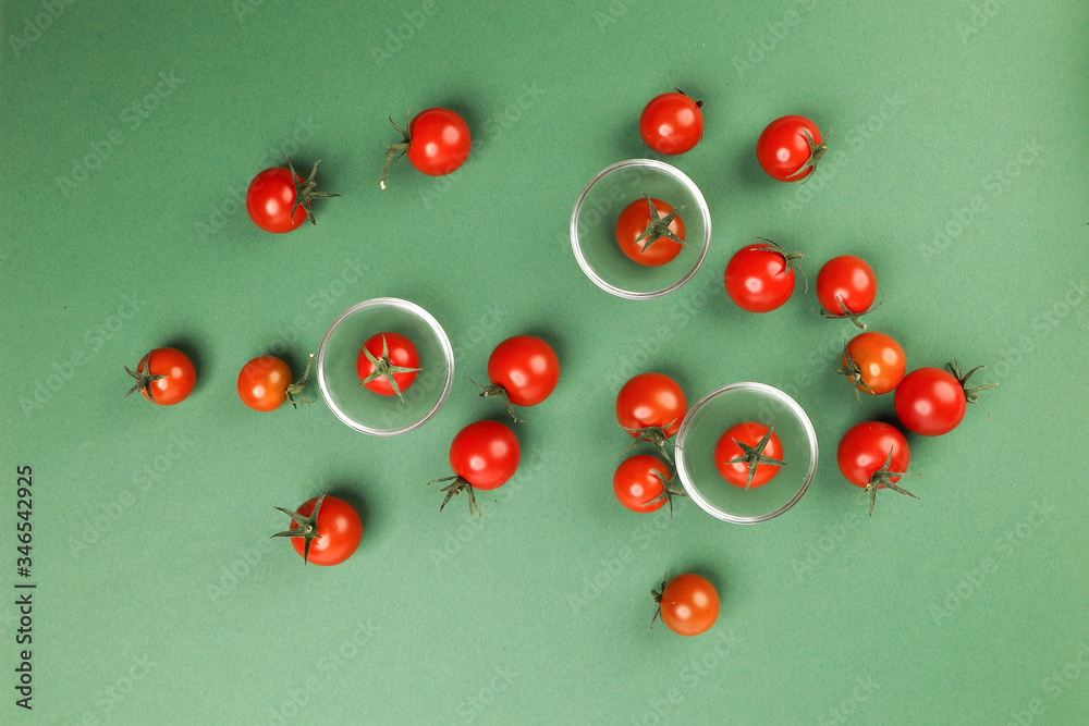 Red ripe cherry tomato with stem on green paper background copy text space mini glass bowl Red ripe cherry tomato with stem on green paper background copy text space mini glass bowl