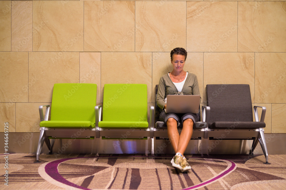Mature beautiful tourist woman using laptop at the lounge indoors