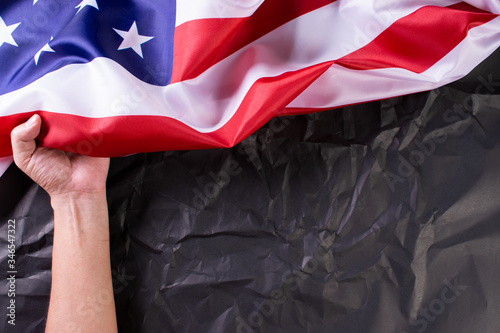 Happy Memorial Day or Independence Day. Man's hand held American flags against a black paper background.