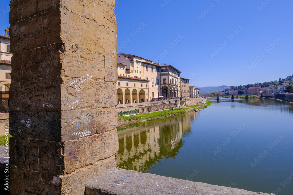 Written messages or love letters on a pillar of the famous Ponte Vecchio, with reflections in the Arno River, Florence