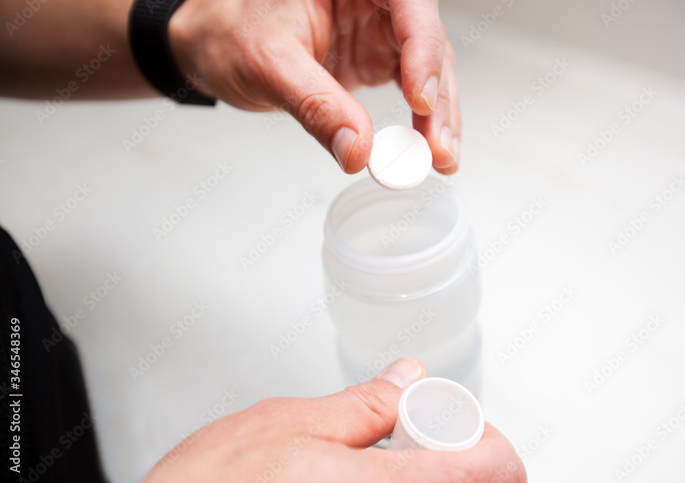 The cyclist is making the isotonic drink putting the effervescent tablets into the water in the plastic bottle The cyclist is making the isotonic drink putting the effervescent tablets into the water in the plastic bottle