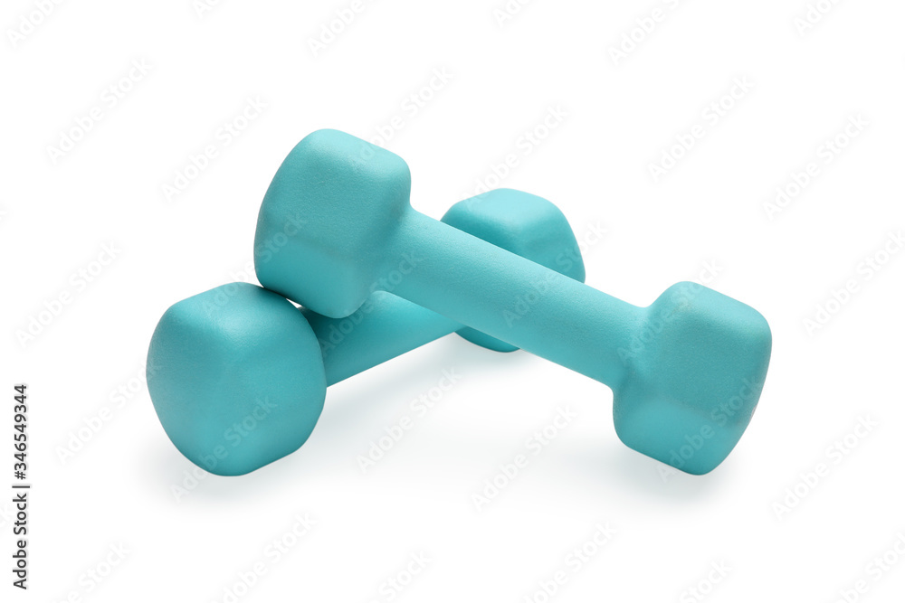 Two turquoise colored rubber dumbbells lying at white table Two turquoise colored rubber dumbbells lying at white table