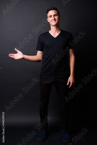 Full body shot of happy young handsome man showing something © Ranta Images