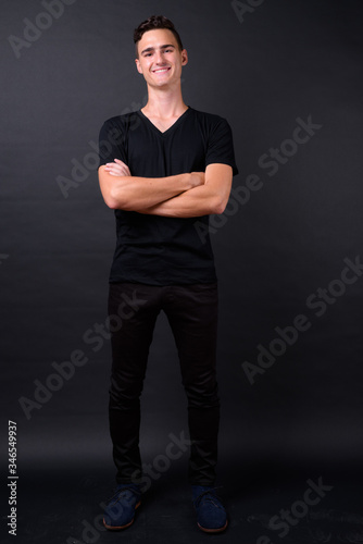 Full body shot of happy young handsome man smiling with arms crossed