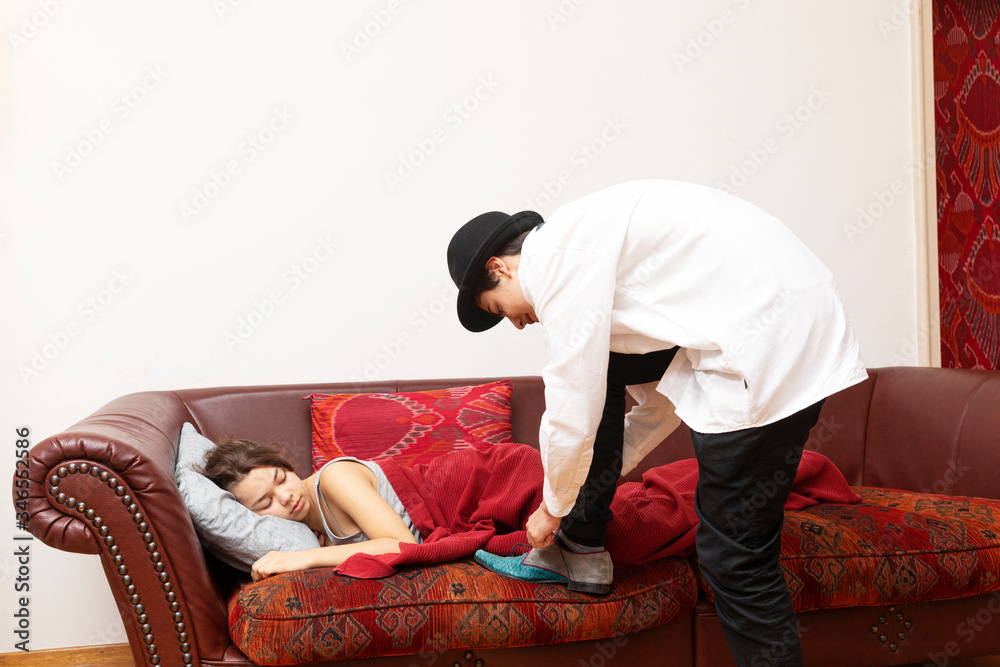 Businessman fastens his shoes while the girl is lying on the sofa with a blanket Businessman fastens his shoes while the girl is lying on the sofa with a blanket