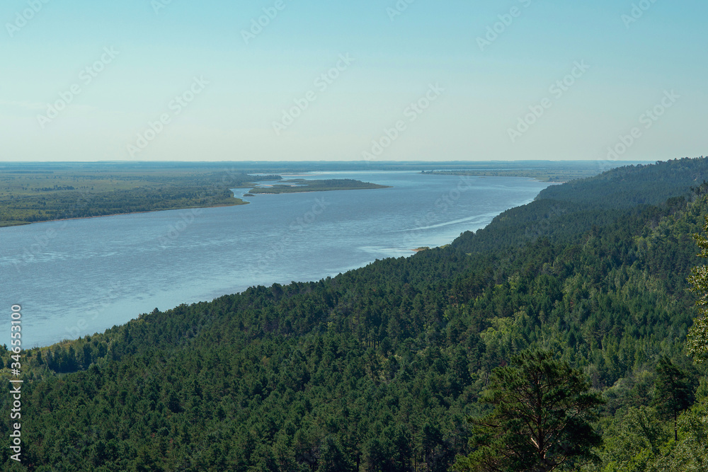 a beautiful view of the river, fields and coniferous forest opens from above