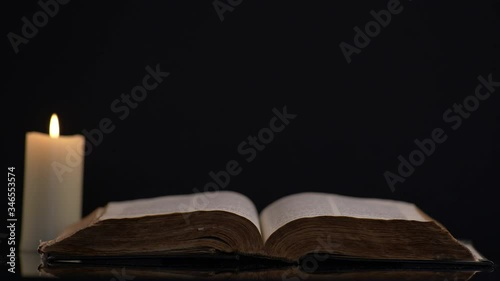 Bible and Lit Candle on Background