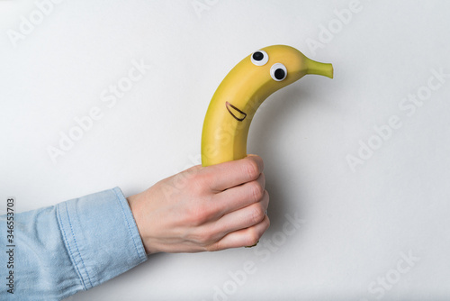 Hand holding banana with funny face. quick snack concept. Vegan