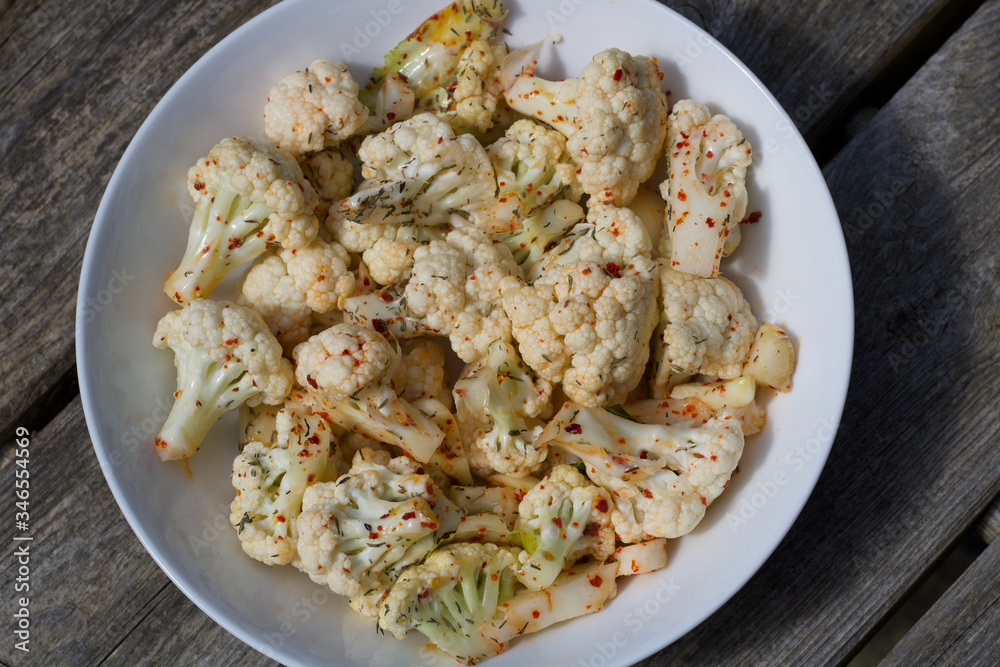 A bowl of spiced cauliflower with red chilli on a plate A bowl of spiced cauliflower with red chilli on a plate