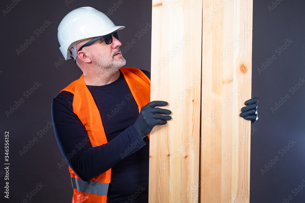 Builder holds wooden planks. Boards in the hands of a man. Conce Builder holds wooden planks. Boards in the hands of a man. Conce