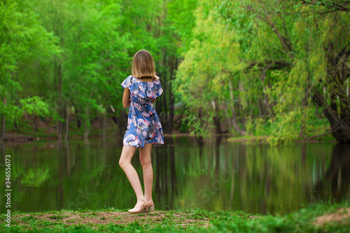 Portrait of a young beautiful woman in blue dress posing by the lake