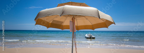 Slika na platnu ombrelloni aperti e sullo sfondo mare  e cielo  blu e un motoscafo pronto a part