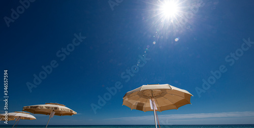 Bilde på lerret ombrelloni aperti e sullo sfondo mare  e cielo  blu e un motoscafo pronto a part
