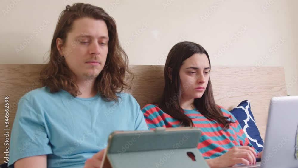 Couple lying in bed occupied with their own laptops. Couple lying in bed occupied with their own laptops.