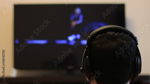 Man in headphones watches a concert on TV