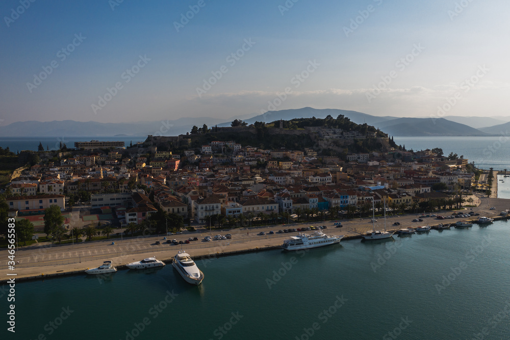 Old town of Nafplion in Greece view from above with tiled roofs, small port and bourtzi castle on the Mediterranean sea water