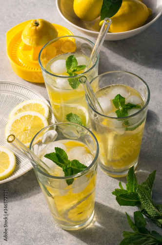 Glasses of homemade lemonade with ice and fresh mint on sunny table. Concept for healthy detox drink.