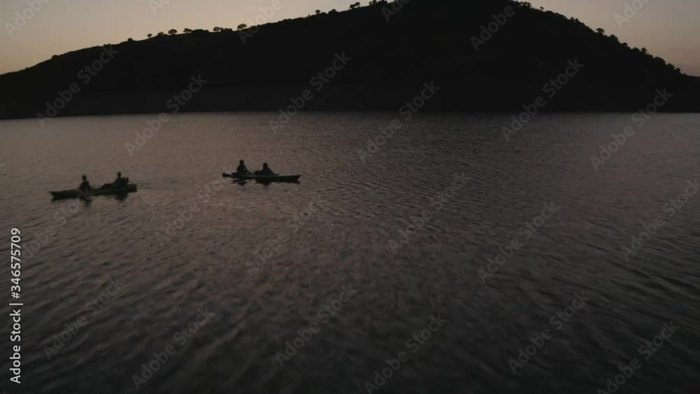 Double canoes sailing through reservoir at sunset Double canoes sailing through reservoir at sunset