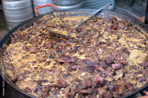 Unhealthy, greasy, oily, mix of meat slices, frying in a large pot, during fast food festival.