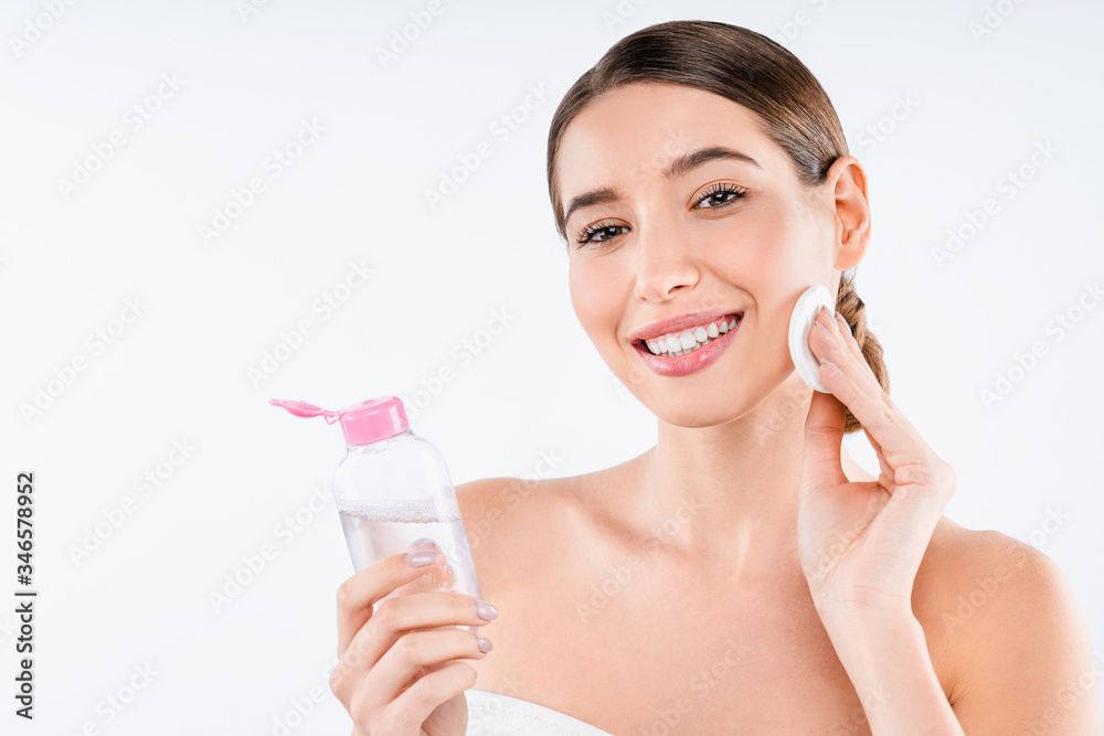 Young caucasian half naked woman using facial lotion with cotton pad isolated over white background Young caucasian half naked woman using facial lotion with cotton pad isolated over white background