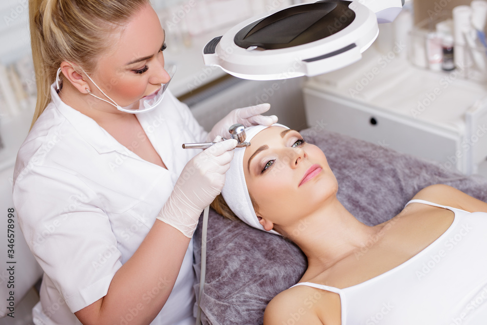 beautiful cosmetologist doing facial oxygen procedure for young woman in modern beauty salon beautiful cosmetologist doing facial oxygen procedure for young woman in modern beauty salon