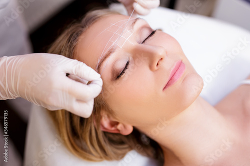 close up of young woman undergoing eyebrow correction procedure in beauty salon