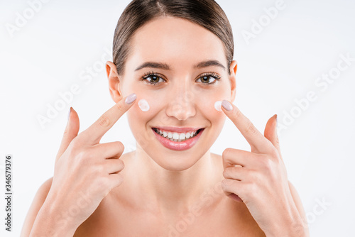 Attractive young woman applying cream on her skin isolated on white background