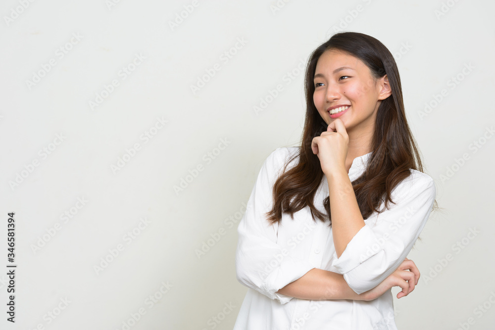 Portrait of happy young beautiful Asian businesswoman thinking Portrait of happy young beautiful Asian businesswoman thinking