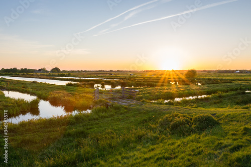 Obraz na plátně Sun sets over the wide open Dutch polder landscape