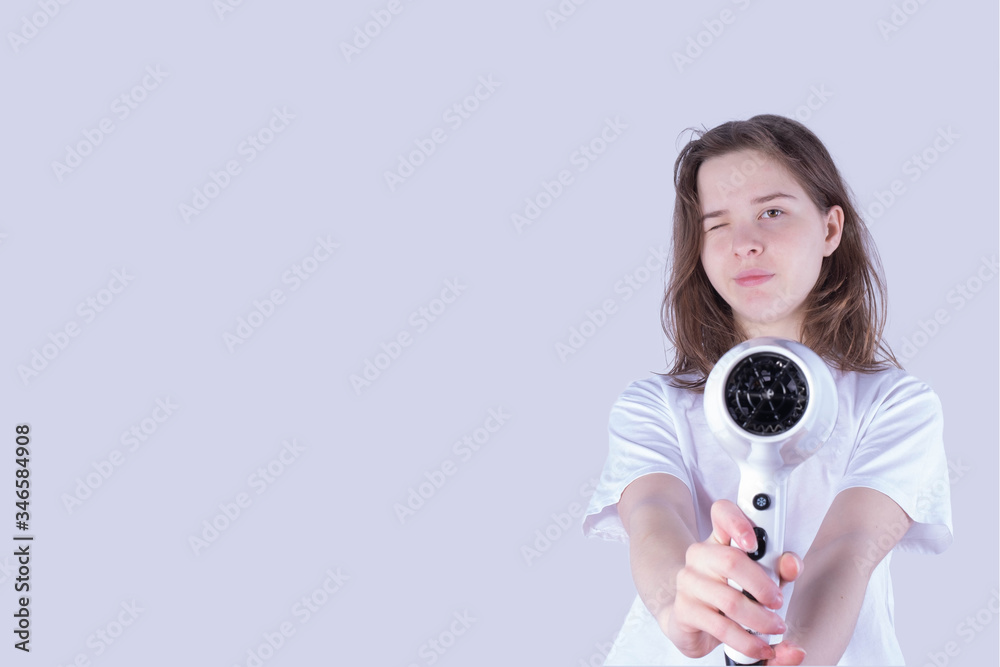 Fototapeta premium young girl holding a hair dryer like a gun