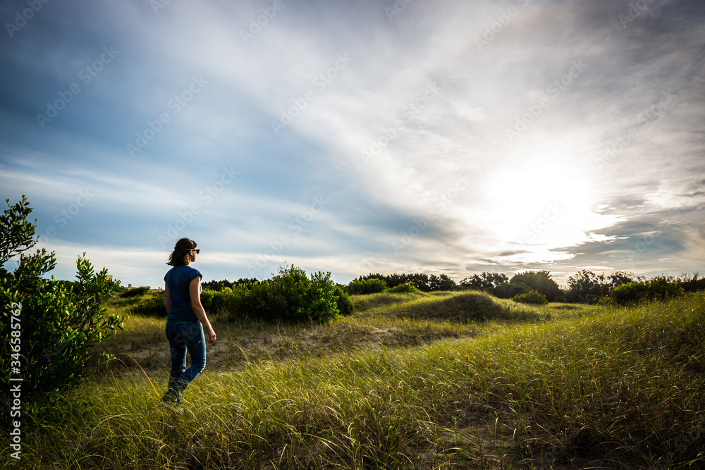 Joven mujer caminando en el pasto al atardecer