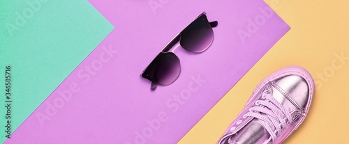 Fashion accessories minimal flat lay. Shoes heels, trendy sunglasses. Pop art concept. Woman fashionable accessories on purple blue, top view, banner. Creative design color