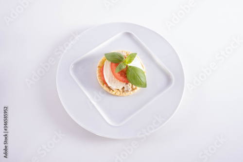 on a plate lies basil, mozzarella and tomato on a corn waffle