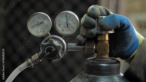 In the workshop. Close-up. The man opens an oxygen cylinder for welding