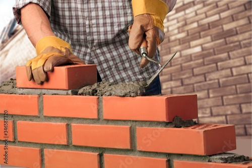 Man worker installing brick masonry wall with a trowel