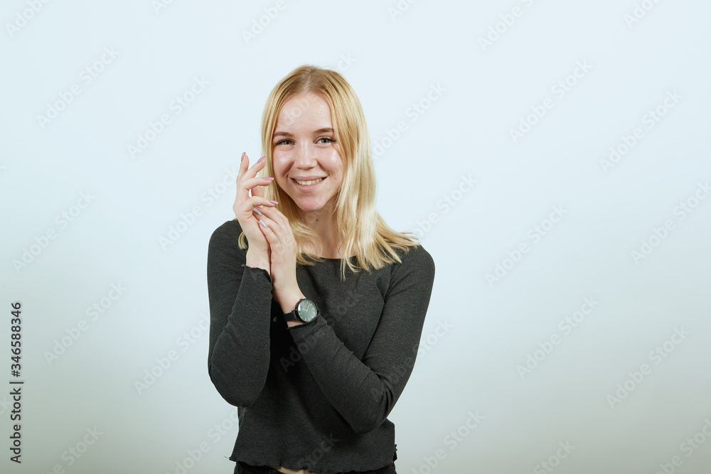Young Blonde Woman In Black Sweater On White Background, Gentle Look Of A Girl, Put The Palms Of Her Hands Together. Concept Of Nice, Kind And Sincere People Young Blonde Woman In Black Sweater On White Background, Gentle Look Of A Girl, Put The Palms Of Her Hands Together. Concept Of Nice, Kind And Sincere People