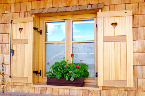 typical mountain building window reflected on glass with flowers