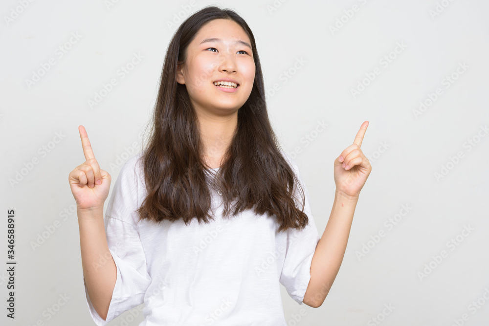 Portrait of happy young beautiful Asian woman pointing up Portrait of happy young beautiful Asian woman pointing up