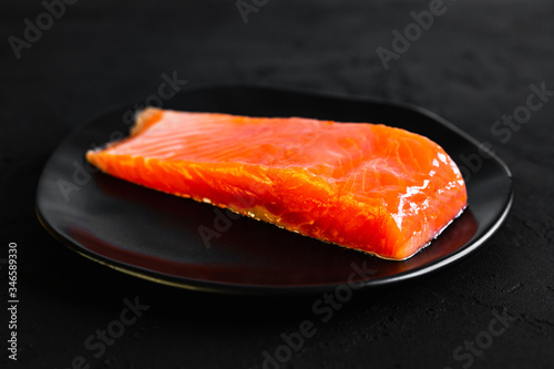 Salted red fish on a black plate on black background, a close-up photo