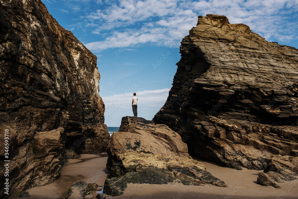man standing on a rock near the beach