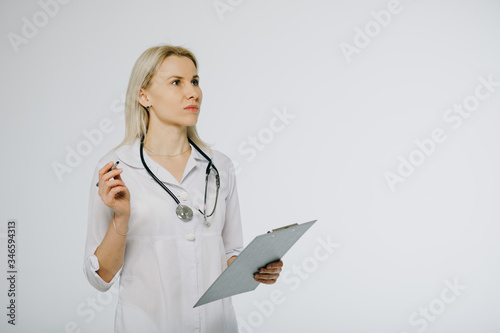 Female doctor in white uniform writing on clipboard paper as copy space for patient's medical history or medicine prescription.