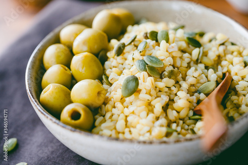 Bulgur with green olives and pepitas, healthy nutrition easy recipe from long-stored food.