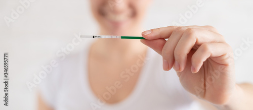 Happy woman shows a positive pregnancy test. The concept of female fertility. Human chorionic gonadotropin. Two stripes expecting a baby. photo