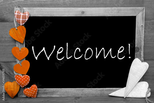 Balckboard With English Text Welcome. Gray Wooden Background With Colored Orange Heart Decoration photo