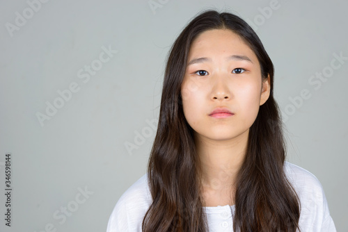 Face of young beautiful Asian woman looking at camera photo